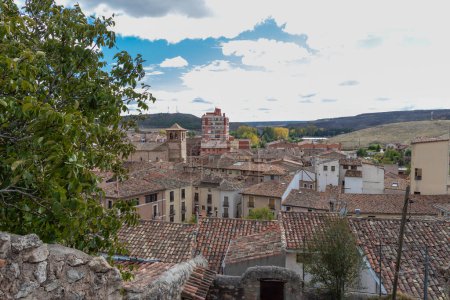 historic town with terracotta rooftops, nestled in nature under a partly cloudy sky
