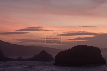 serene sunset with silhouetted mountains and rock formations against a gradient sky, evoking peace and tranquility in san juan de gaztelugatxe