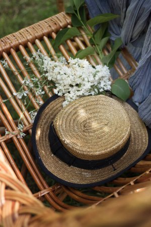 Téléchargez les photos : Chapeau de paille, fleurs blanches et une chaise en osier - en image libre de droit