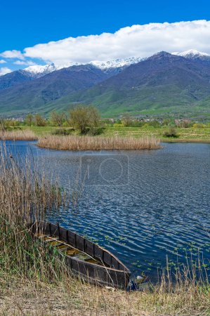 View of  Kerkini Lake in northern Greece with traditional wooden fishing boat and part of snowy Mount Beles