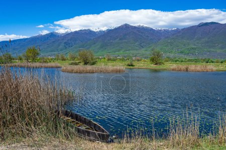 Vista del lago Kerkini en el norte de Grecia con barco pesquero tradicional de madera y parte del nevado Monte Beles
