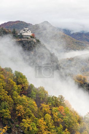 Photo for View of the Metamorphosis Sotiros monastery in a landscape with autumnal colorful foliage and clouds at Mount Rodopi, near the village of Paranesti in northern Greece - Royalty Free Image
