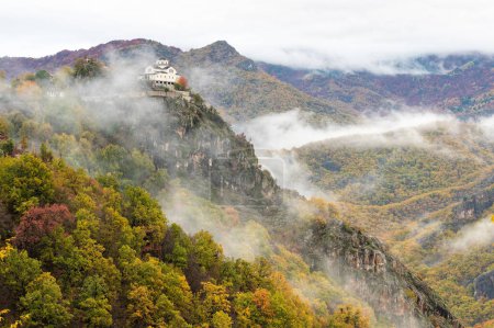 Photo for View of the Metamorphosis Sotiros monastery in a landscape with autumnal colorful foliage and clouds at Mount Rodopi, near the village of Paranesti in northern Greece - Royalty Free Image