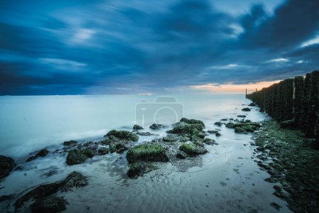 Küste mit Buhnen und Basaltsteinen bei stürmischem Wetter im Dorf Westkappelle auf Walcheren in der Provinz Zeeland, Niederlande