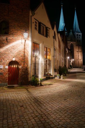 Stadtpanorama bei Nacht mit beleuchteten Straßen und monumentalen Gebäuden im holländischen Deventer in den Niederlanden