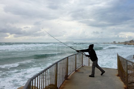 Téléchargez les photos : Pêcheur capture des poissons en mer par temps orageux - en image libre de droit