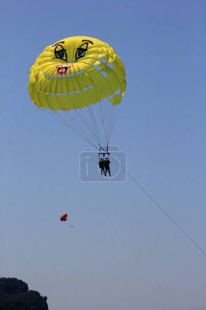 Photo for Parasailing in a blue sky near Budva beach, yellow parachute with people - Royalty Free Image