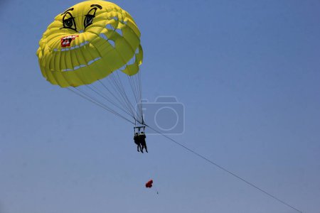 Photo for Parasailing in a blue sky near Budva beach, yellow parachute with people - Royalty Free Image