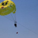 Parasailing in a blue sky near Budva beach, yellow parachute with people