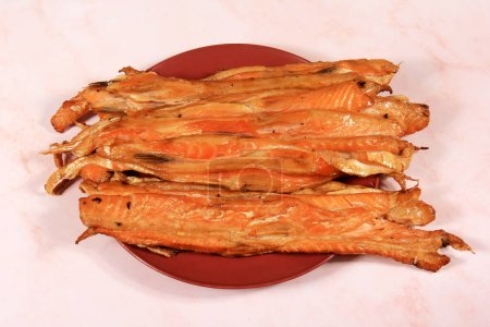 Photo for Slices of smoked salmon belly on red plate, pink background. fish snack - Royalty Free Image