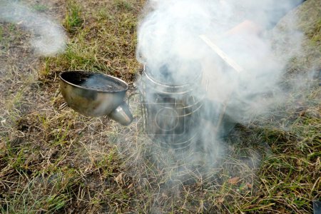   Close up of a beekeepers smoking equipment with smoke and fire coming out of the nozzle                             