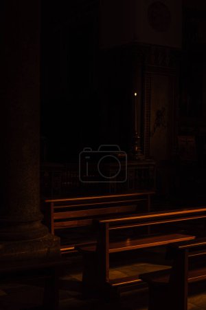 Schattiges Interieur einer Kathedrale in Italien. Ein Rohbau aus Holzbänken im Dunkeln.