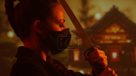Téléchargez les photos : Jeune et belle fille ninja dans un masque et avec un katana. Femme samouraï sur le fond d'un temple japonais traditionnel. - en image libre de droit