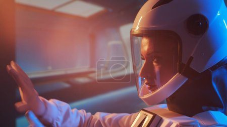 Foto de Una astronauta con traje espacial a bordo de la estación orbital. Una joven cosmonauta pilota una nave espacial. El concepto de viaje galáctico y ciencia. - Imagen libre de derechos