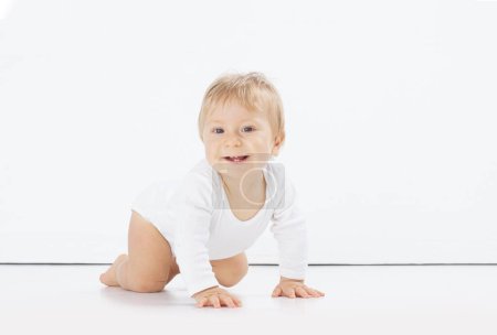 Foto de Pequeño, feliz y sonriente bebé lindo en el estudio. Retrato de un bebé de un año. Fondo blanco aislado. El concepto de felicidad. - Imagen libre de derechos