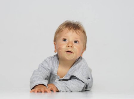 Foto de Pequeño, feliz y sonriente bebé lindo en el estudio. Retrato de un bebé de un año. Fondo gris. El concepto de felicidad. - Imagen libre de derechos