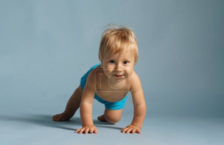 Téléchargez les photos : Petit, heureux et souriant bébé mignon dans le studio. Portrait d'un bébé d'un an. Fond bleu. Le concept de bonheur. - en image libre de droit