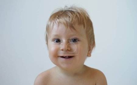 Téléchargez les photos : Petit, heureux et souriant bébé mignon dans le studio. Portrait d'un bébé d'un an. Fond gris. Le concept de bonheur. - en image libre de droit