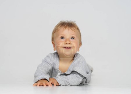 Photo for Little, happy and smiling cute baby in the studio. Portrait of a one year old baby. Grey background. The concept of happiness. - Royalty Free Image