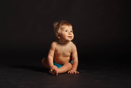 Foto de Pequeño, feliz y sonriente bebé lindo en el estudio. Retrato de un bebé de un año. Fondo negro. El concepto de felicidad. - Imagen libre de derechos