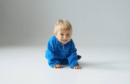 Téléchargez les photos : Petit, heureux et souriant bébé mignon dans le studio. Portrait d'un bébé d'un an. Fond gris. Le concept de bonheur. - en image libre de droit