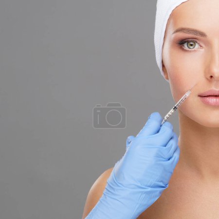 Téléchargez les photos : Docteur injectant dans un beau visage d'une jeune femme. Chirurgie plastique, lifting de la peau et médecine esthétique concept. - en image libre de droit