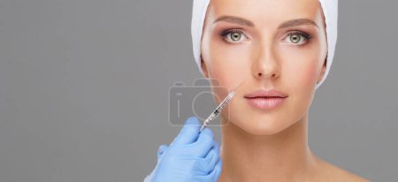 Téléchargez les photos : Docteur injectant dans un beau visage d'une jeune femme. Chirurgie plastique, lifting de la peau et médecine esthétique concept. - en image libre de droit