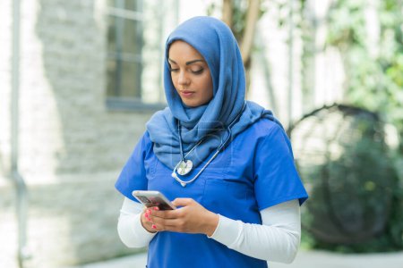 Photo for Close-up portrait of young and attractive muslim woman nurse in hijab. Middle Eastern female doctor outdoor on the street. City background. The concept of medicine and health care. - Royalty Free Image