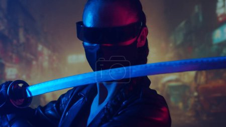 Téléchargez les photos : Cyberpunk ninja fille dans un masque et avec un katana. Belle femme samouraï sur le fond de la ville asiatique rue du centre-ville. - en image libre de droit