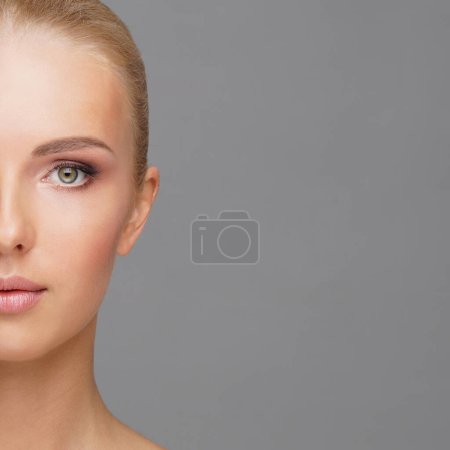 Photo for Beautiful face of young and healthy girl over grey background. Skin care, cosmetics and face lifting concept. - Royalty Free Image
