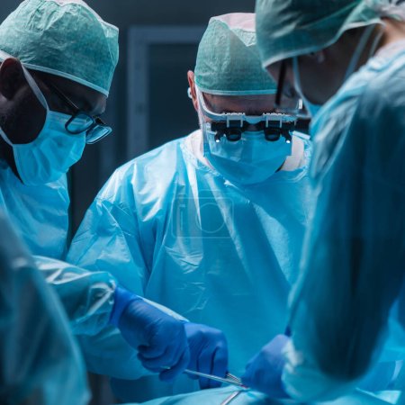 Une équipe diversifiée de médecins professionnels effectue une opération chirurgicale dans une salle d'opération moderne à l'aide d'équipements et de technologies de pointe. Les chirurgiens travaillent pour sauver le patient à l'hôpital