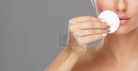 Photo for Young woman cleaning her face with a cotton pads. Girl removing cosmetics with hygienic discs. Cosmetology concept. - Royalty Free Image