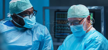 Photo for Diverse team of professional medical doctors performs a surgical operation in a modern operating room using high-tech equipment and technology. Surgeons are working to save the patient in the hospital - Royalty Free Image