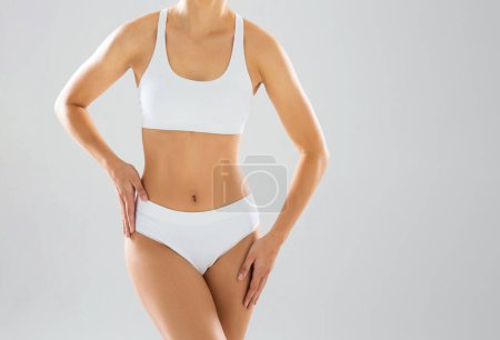 Photo for Young and beautiful slender girl in white swimsuit posing over white background. The concept of healthcare, diet, sport and fitness. - Royalty Free Image