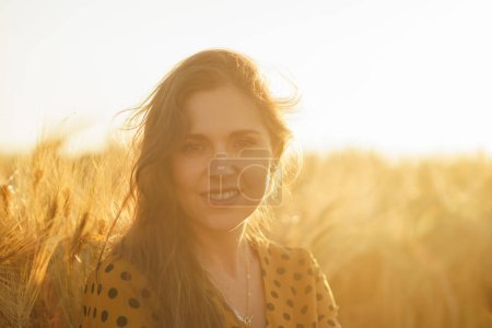 Foto de Retrato de cerca de una hermosa joven en un campo. Cara femenina en los rayos del atardecer. Concepto de libertad y felicidad. - Imagen libre de derechos