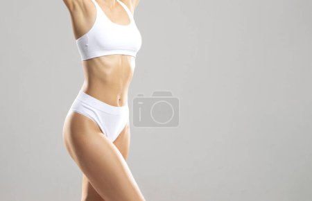 Foto de Joven y hermosa chica delgada en traje de baño blanco posando sobre fondo blanco. El concepto de salud, dieta, deporte y fitness. - Imagen libre de derechos