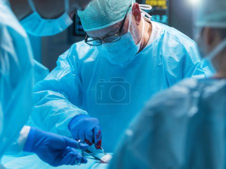 Ein vielseitiges Team professioneller Ärzte führt einen chirurgischen Eingriff in einem modernen Operationssaal mit High-Tech-Geräten und -Technologie durch. Chirurgen arbeiten daran, den Patienten im Krankenhaus zu retten