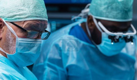 Une équipe diversifiée de médecins professionnels effectue une opération chirurgicale dans une salle d'opération moderne à l'aide d'équipements et de technologies de pointe. Les chirurgiens travaillent pour sauver le patient à l'hôpital