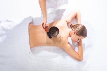 Young woman getting massaging treatment over white background. Spa, healthcare and recreation concept.