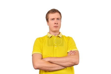 Téléchargez les photos : Suspicious guy crossed arms on his chest, proud look isolated on white background. Young doubtful man in yellow T-shirt with crossed arms, gesture of defensiveness, body language - en image libre de droit