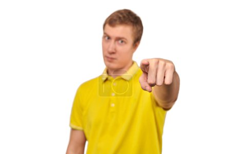Téléchargez les photos : Handsome guy in casual yellow Polo T-shirt pointing finger forward isolated on white background. Funny short-haired man pointing forward, indicates goal, guy pointing at camera - en image libre de droit