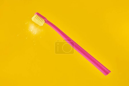 Téléchargez les photos : Pink toothbrush on yellow background for oral hygiene to clean teeth, gums and tongue. Manual plastic toothbrush with fresh shine near bristle isolated on yellow background - en image libre de droit