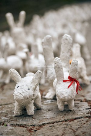Foto de White rabbit statues made of plaster at outdoor art exhibition, artificial white hares on city street. A lot of white handmade rabbits, many decorative bunnies, Easter urban decor concept - Imagen libre de derechos