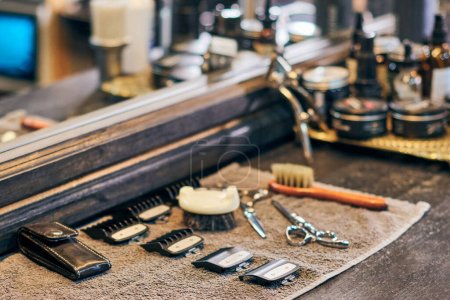 Foto de Barbershop haircut tools barber equipment on wooden countertop front of mirror, old vintage style interior. Hairdresser tools for stylish hair cut, clipper guide combs, scissors and hairbrushes - Imagen libre de derechos