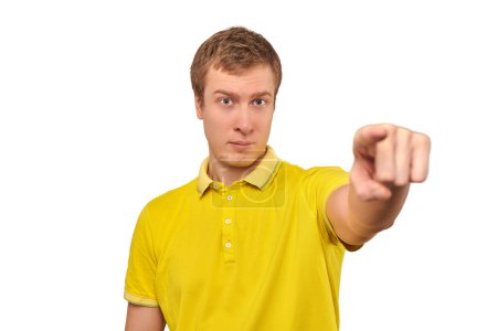 Téléchargez les photos : Handsome guy in casual yellow Polo T-shirt pointing finger forward isolated on white background. Funny short-haired man pointing forward, indicates goal, guy pointing at camera - en image libre de droit