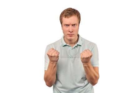 Téléchargez les photos : Angry young man in light grey T-shirt ready to fight with fists isolated on white background. Confident annoyed guy ready to fistfight, defense gesture, aggressive man with clenched fists - en image libre de droit