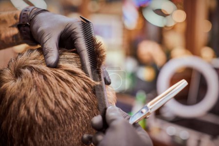 Photo for Male haircut in barbershop close up, client getting haircut by hairdresser with comb and scissors. Hairdresser makes hairdo in hairdresser salon, new stylish modern haircut for man - Royalty Free Image