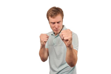 Téléchargez les photos : Angry young man in light grey T-shirt ready to fight with fists isolated on white background. Aggressive handsome man going to fistfight, defense gesture, bad guy with clenched fists - en image libre de droit