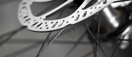 Photo for Bicycle disk brakes close up, grey metal disc attached to bike wheel, effective popular mountain bicycle brakes. Hydraulic disk brakes on bicycle wheel, bicycle spokes gray background - Royalty Free Image