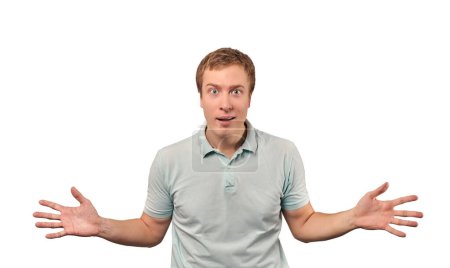 Foto de Confused young man shrugged shoulders, male in green casual T-shirt spread arms isolated on white background. Puzzled young man spread his hands, bewildered don't know gesture - Imagen libre de derechos